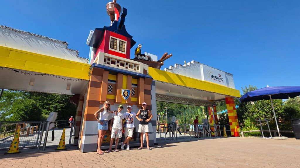 make-a-wish-oesterreich_erfuellte-wuensche_Fabian (10) Fabian mit Familie am Eingang des LEGOLAND Feriendorfs mit Lego-Turm im Hintergrund.