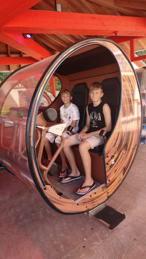 make-a-wish-oesterreich_erfuellte-wuensche_Fabian (2) Zwei Jugendliche sitzen während Fabians Make-A-Wish-Wunscherfüllung gemeinsam in einer Fahrgeschäft-Kabine.