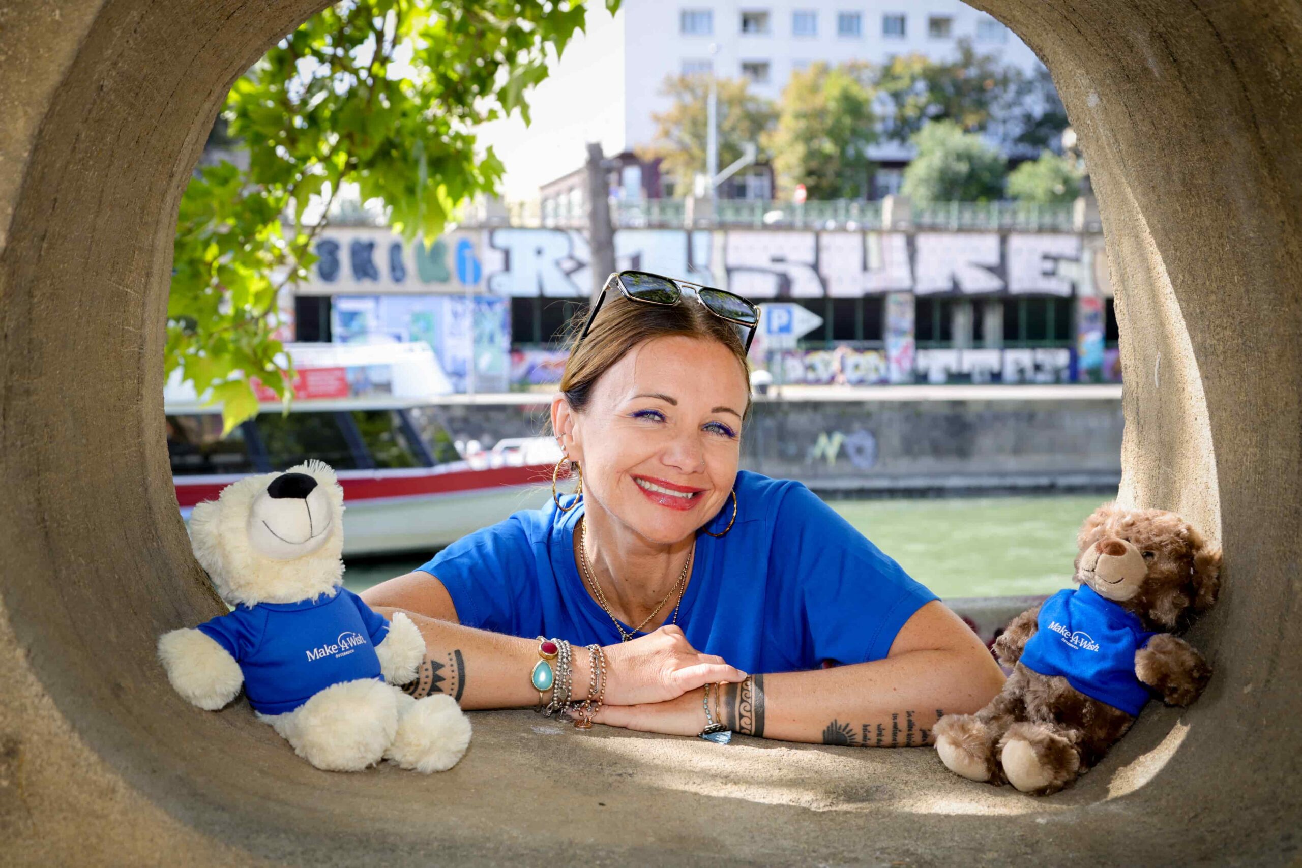 Simone Wagner durch eine Betonröhre fotografiert, in der 2 Hope-Teddy-Bären sitzen.